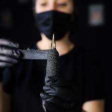 Close-up of a tattoo device held by a gloved practitioner