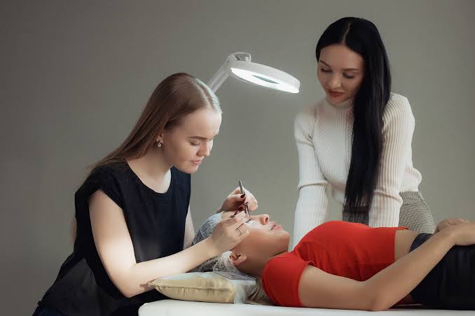 Instructor observing a student applying eyelash extensions